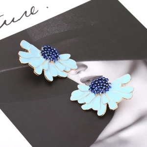 Detail of blue daisy earrings with enamel petals and gold alloy base on art magazine