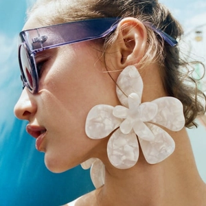 Boucles d'oreilles fleurs en acrylique blanc avec texture marbrée sur un mannequin