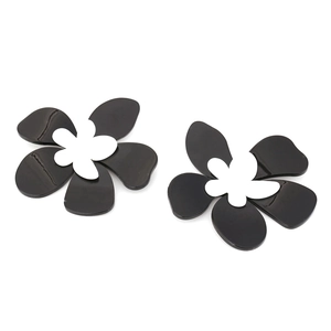 Détail de boucles d'oreilles fleurs en acrylique noir superposées avec centre blanc poli