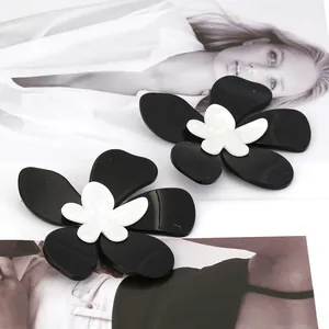 Gros plan de grandes boucles d'oreilles fleur en acrylique au design 3D noir et blanc