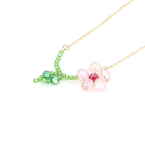 Pink and green crystal flower pendant on a fine golden necklace with a white background