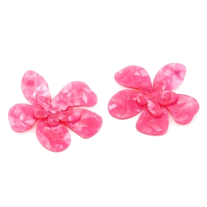 Détail macro montrant la texture marbrée rose sur les boucles d'oreilles fleurs