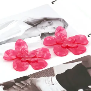 Détail de boucles d'oreilles fleurs en acrylique rose avec texture marbrée chic