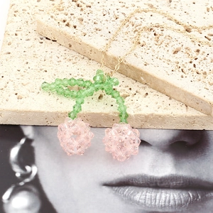 Macro detail of handmade beaded pink crystal cherry pendant on elegant gold chain necklace