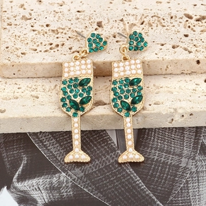 Détail de boucles d'oreilles en verre à champagne avec cristaux verts et perles
