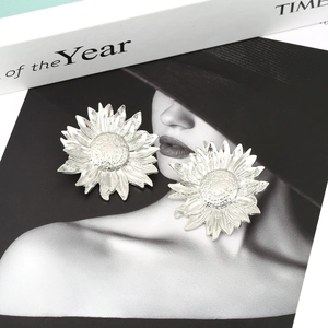Detailed view of silver sunflower earrings with textured petals on a creative background