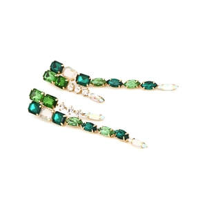Exaggerated geometric gold drop earrings with emerald green crystals and long tassel fringe
