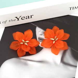 Macro detail of Bohemian resin flower earrings with orange petals and golden stamens