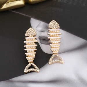 Exaggerated golden fishbone earrings featuring white pearls and sparkling rhinestones