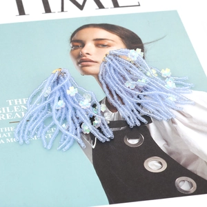 Handmade light blue beaded tassel earrings with iridescent white flowers on a magazine cover