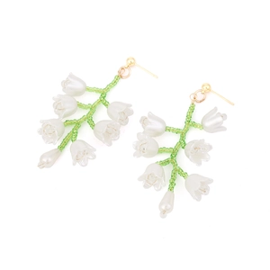 Détail de boucles d'oreilles muguet fait main avec pétales blancs et tiges vertes