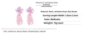 Détail de boucles d'oreilles fleur avec pétales en résine violette et pompons roses