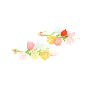 Détail de boucles d'oreilles fleurs mates colorées avec perles vertes et gouttes
