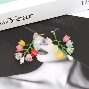 Détail des boucles d'oreilles muguet faites à la main sur fond de magazine de mode