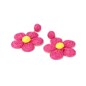 Detailed view of handmade woven raffia flower earrings with pink petals and yellow center