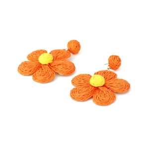 Macro shot of orange raffia woven flower earrings with yellow centers in bohemian style