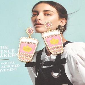 Detail of pink juice cup earrings with pearls and crystals on blue magazine background