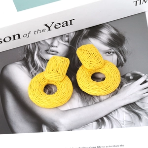 Details von leuchtend gelben, handgewebten Bastohrringen mit geometrischen Kreisen auf Magazin