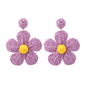 Handmade raffia flower drop earrings with purple petals and yellow core in boho style
