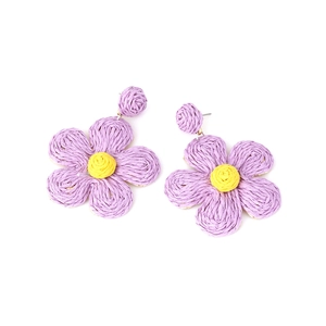 Detailed macro of handmade purple and yellow raffia flower drop earrings in bohemian style