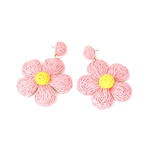 Close-up of handmade pink and yellow raffia woven flower earrings in a bohemian style