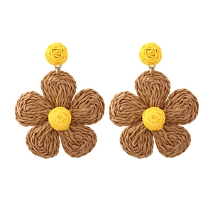 Detail of handmade raffia flower earrings in yellow and brown bohemian weave style