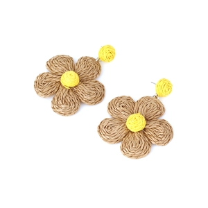 Close-up of handmade woven raffia flower earrings in brown and yellow bohemian style