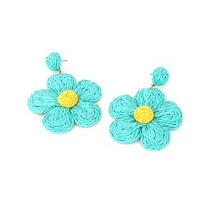 Close-up of handmade woven raffia flower earrings in turquoise and yellow colors