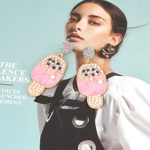 Vibrant enamel ice cream earrings with colorful crystals and pearls on magazine background
