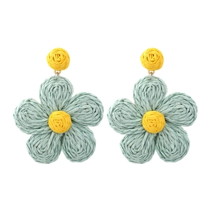 Macro detail of hand-woven raffia flower earrings in mint green and yellow colors