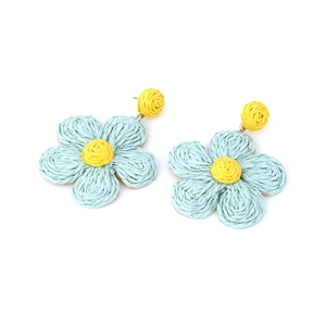 Detailed close-up of handmade blue raffia flower earrings with bohemian woven texture