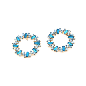 Dettaglio di orecchini dorati con cristalli blu rettangolari in un design circolare