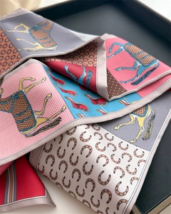 Detail of equestrian print silk scarf showing horses and stirrups on smooth fabric