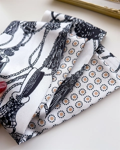 Dettaglio di un foulard in seta bianco e nero con lussuosi motivi a catena dorata