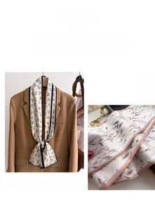 Detailed view of floral silk scarf with black piping on elegant beige background