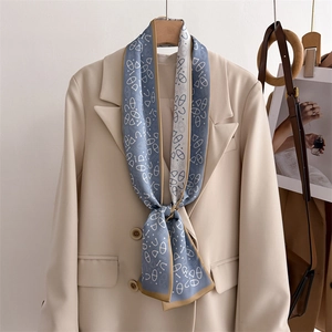 Detail view of a luxury blue silk twilly scarf tied on a beige suit collar