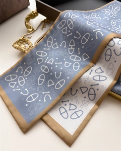 Macro shot of grey-blue silk twilly scarf with horse bit and letter patterns