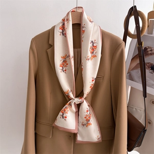 Detail of silk scarf with orange persimmon print tied on a blazer lapel elegantly