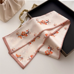 Detail of floral print silk scarf in cream and orange on elegant black tray setup