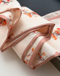 Detailed view of silk scarf with orange persimmon print and soft pink edges