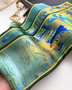 Detailed view of elegant green silk scarf with artistic landscape print and yellow trim