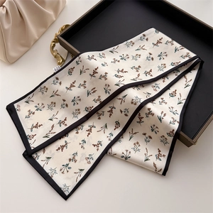 Detail of floral silk twilly scarf with black edges on an elegant display tray