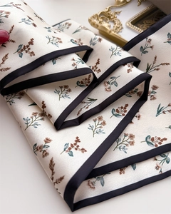 Detail of silk scarf with floral print, black borders and elegant satin texture finish