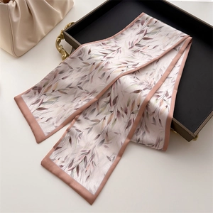 Detail of pink-purple floral printed silk ribbon scarf tied on a beige luxury pleated bag