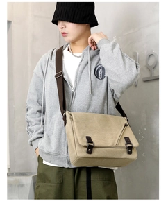 Detail of khaki canvas messenger bag with adjustable strap and leather buckle closures