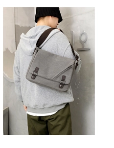Detailed back view of a gray canvas messenger bag with brown straps on a male model