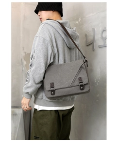 Men's grey canvas messenger bag worn by model showing its spacious design and strap