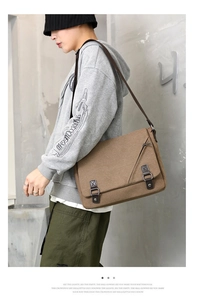 Detailed view of brown canvas messenger bag with double buckles and vintage workwear style