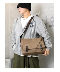 Close-up of brown canvas messenger bag with leather straps on a male model for street style