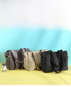 Close-up of three canvas tote bags in grey, beige and black with side pockets and texture